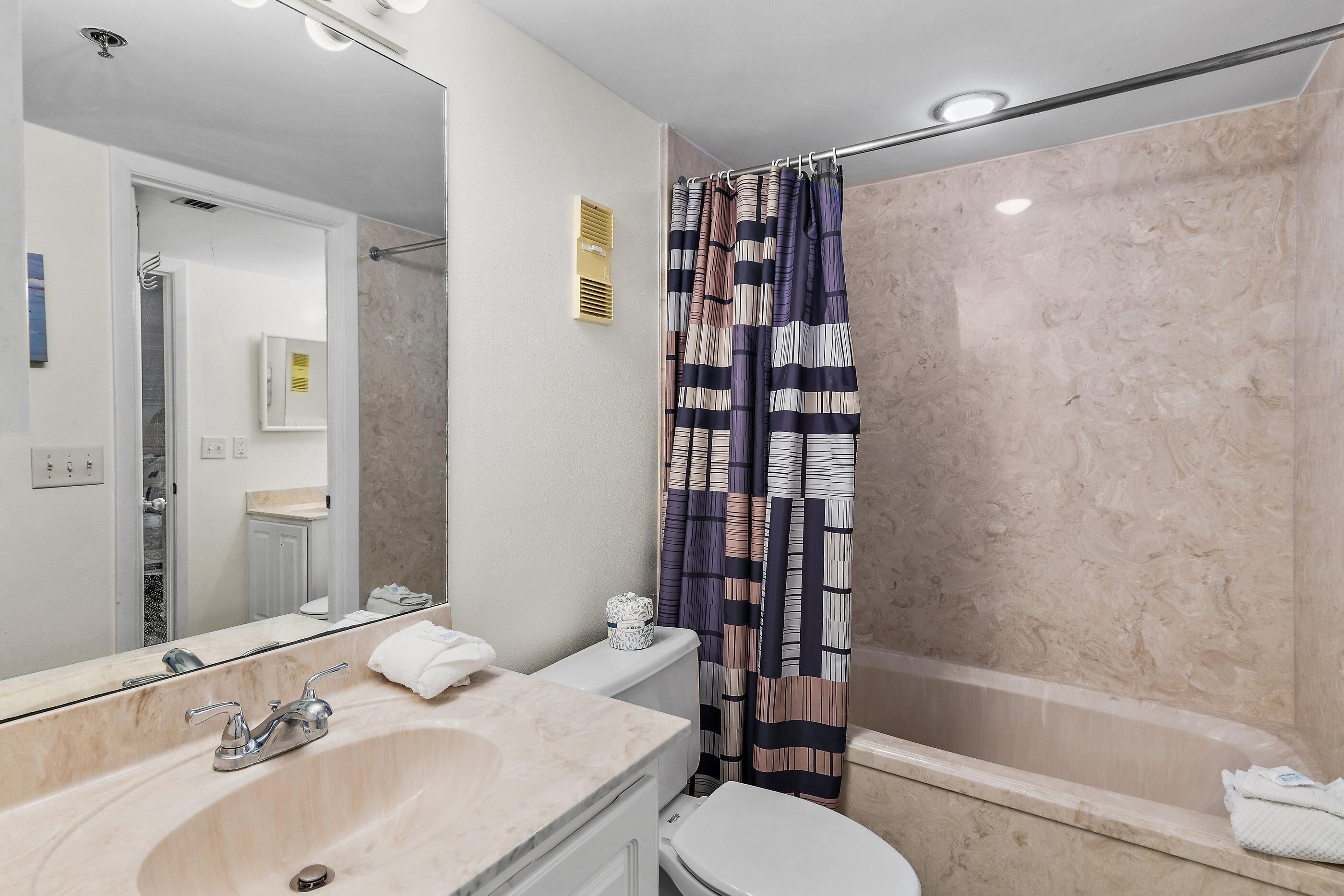 Une salle de bain avec un grand miroir, un lavabo, des toilettes et un espace douche.