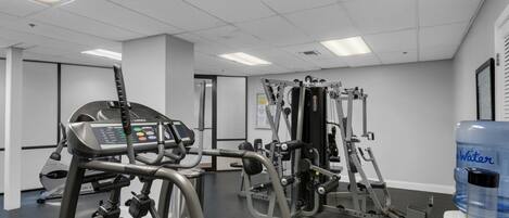 A gym with cardio machines, weight training equipment, and a water dispenser.