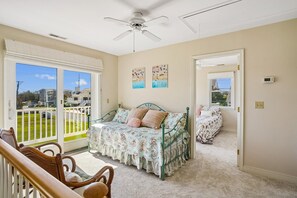 Une chambre à coucher avec un lit, une chaise, un ventilateur de plafond et une vue par la fenêtre.
