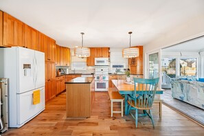 Une cuisine moderne avec des meubles en bois, un îlot central et un coin repas avec des chaises bleues.