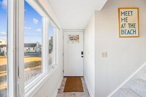 A hallway with a view of a beach, a door with a window, and a framed sign on the wall. - Coastal Retreat in South Bethany (South Bethany)