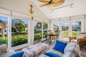 A sunroom with large windows, a ceiling fan, and a view of a canal. - Coastal Retreat in South Bethany (South Bethany)