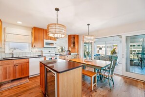 A modern kitchen with wooden cabinets, a central island, and pendant lighting. - Coastal Retreat in South Bethany (South Bethany)