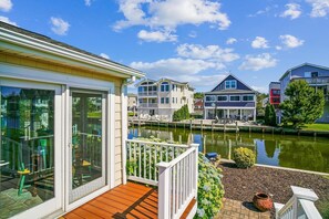 A waterfront property with a wooden deck, a glass-enclosed room, and a view of neighboring houses. - Coastal Retreat in South Bethany (South Bethany)