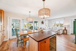 A spacious living area with a large sofa, a dining table, and a kitchen island. - Coastal Retreat in South Bethany (South Bethany)
