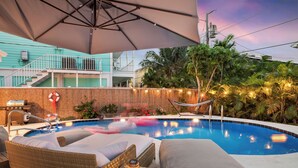 A pool area with lounge chairs, a hammock, and a grill. - Walk to Beach- Private Pool • Mini Golf • Firepit (Redington Beach)