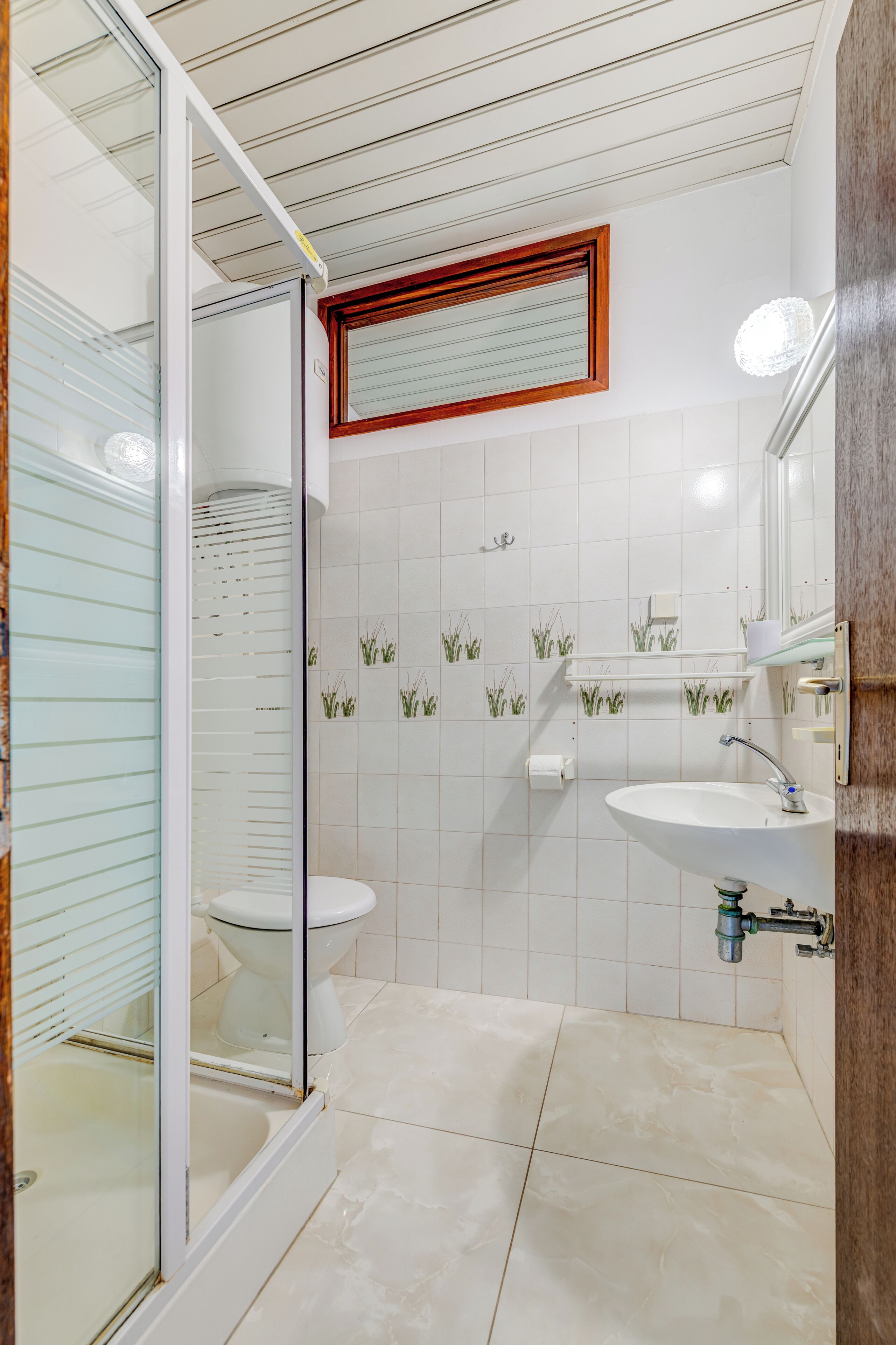 Un baño con cabina de ducha de vidrio, inodoro, lavabo y espejo.