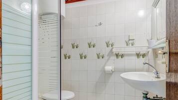 Un baño con cabina de ducha de vidrio, inodoro, lavabo y espejo.