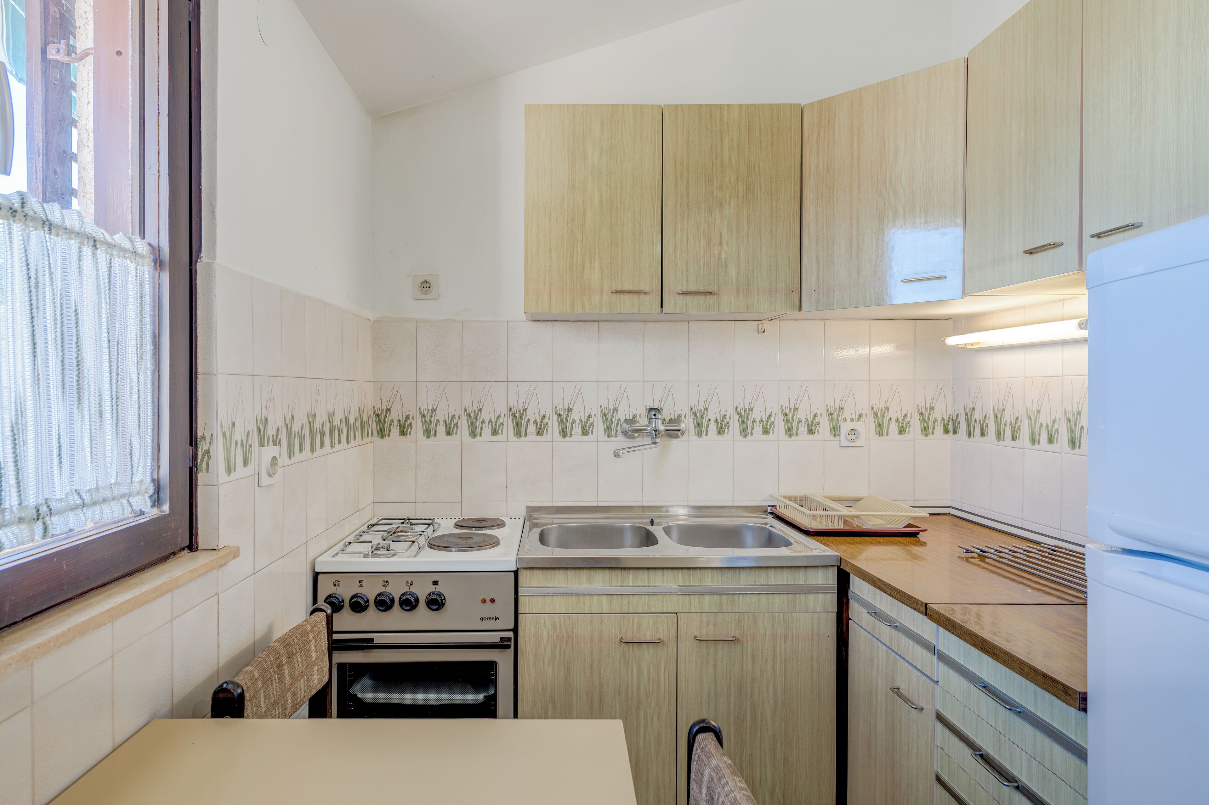 A kitchen with a gas stove, double sink, and wooden cabinets.