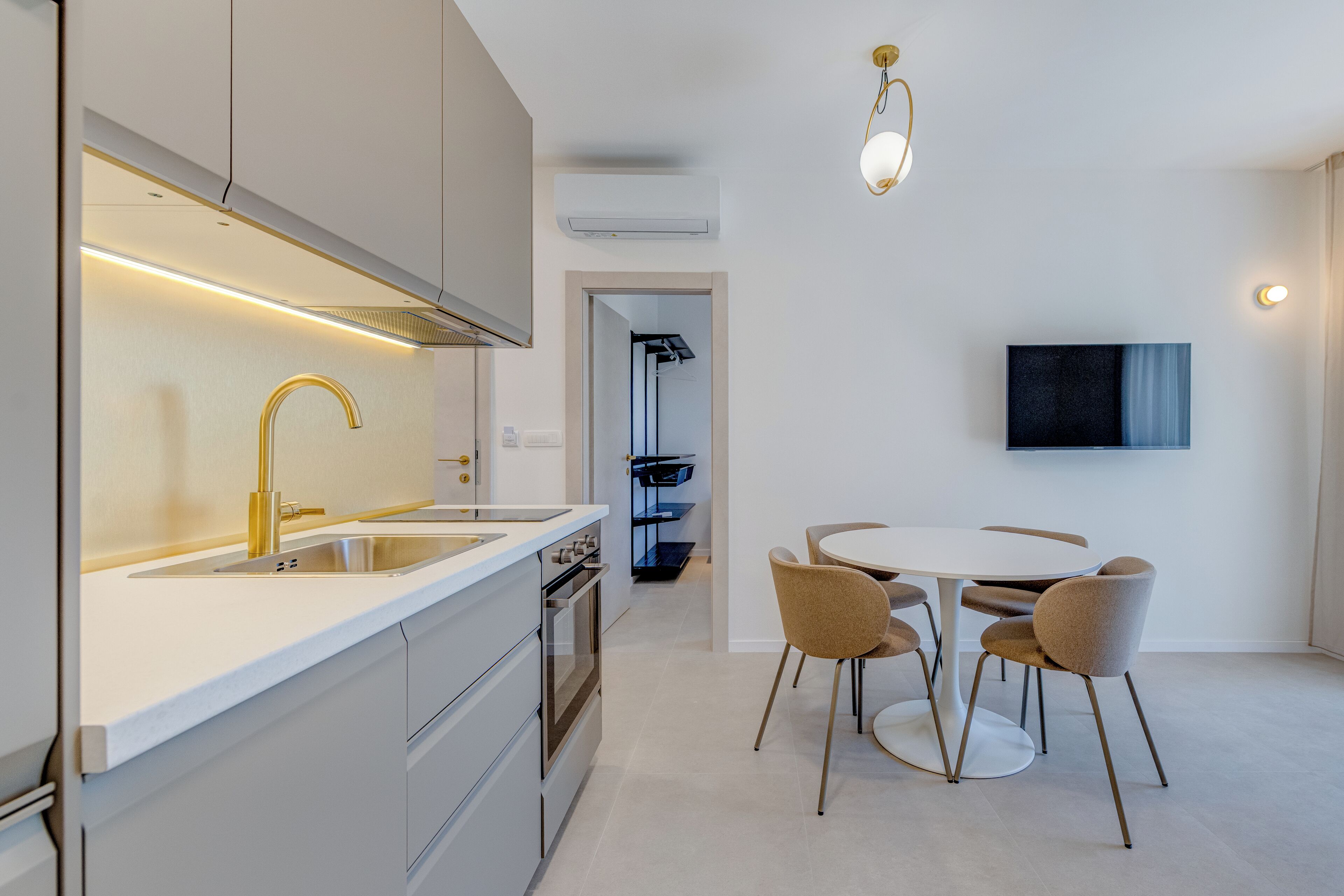 A modern kitchen with a built-in oven, a stainless steel sink, and a dining area with a round table and chairs.