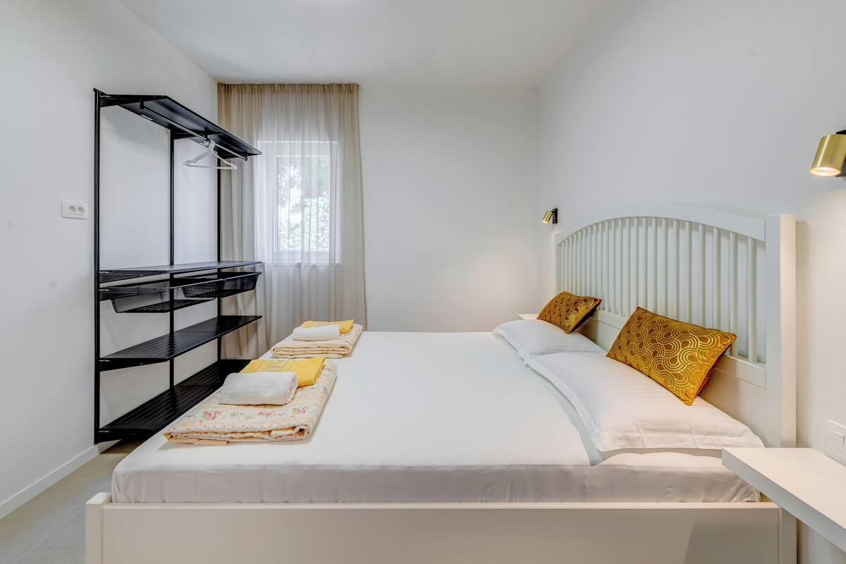 A hotel room with a bed, a wardrobe, a bedside table, and a window with curtains.