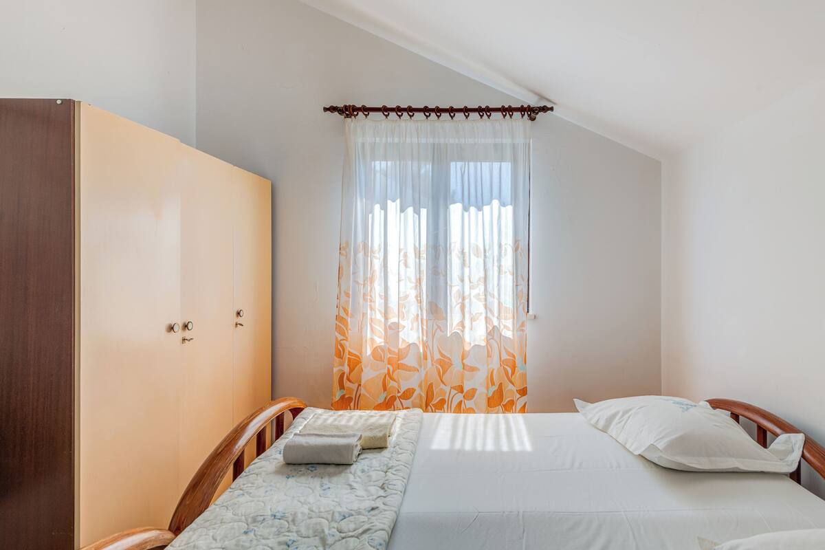 A bedroom with a bed, a wardrobe, and a window with curtains.