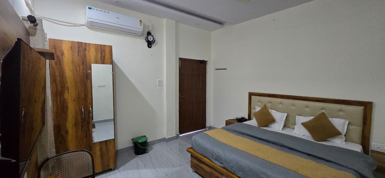 A bedroom with a bed, a wardrobe, a mirror, and a door.