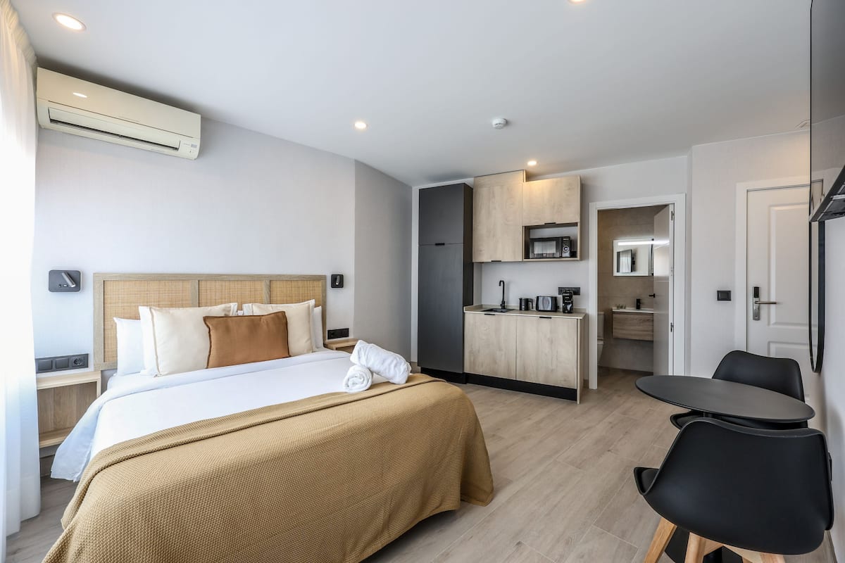 Ein Hotelzimmer mit Bett, Schreibtisch, Stuhl, einer Küchenzeile und einem Badezimmer.