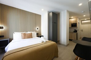 Habitación de hotel moderna con una cama bien hecha, un escritorio pequeño y una zona de kitchenette.