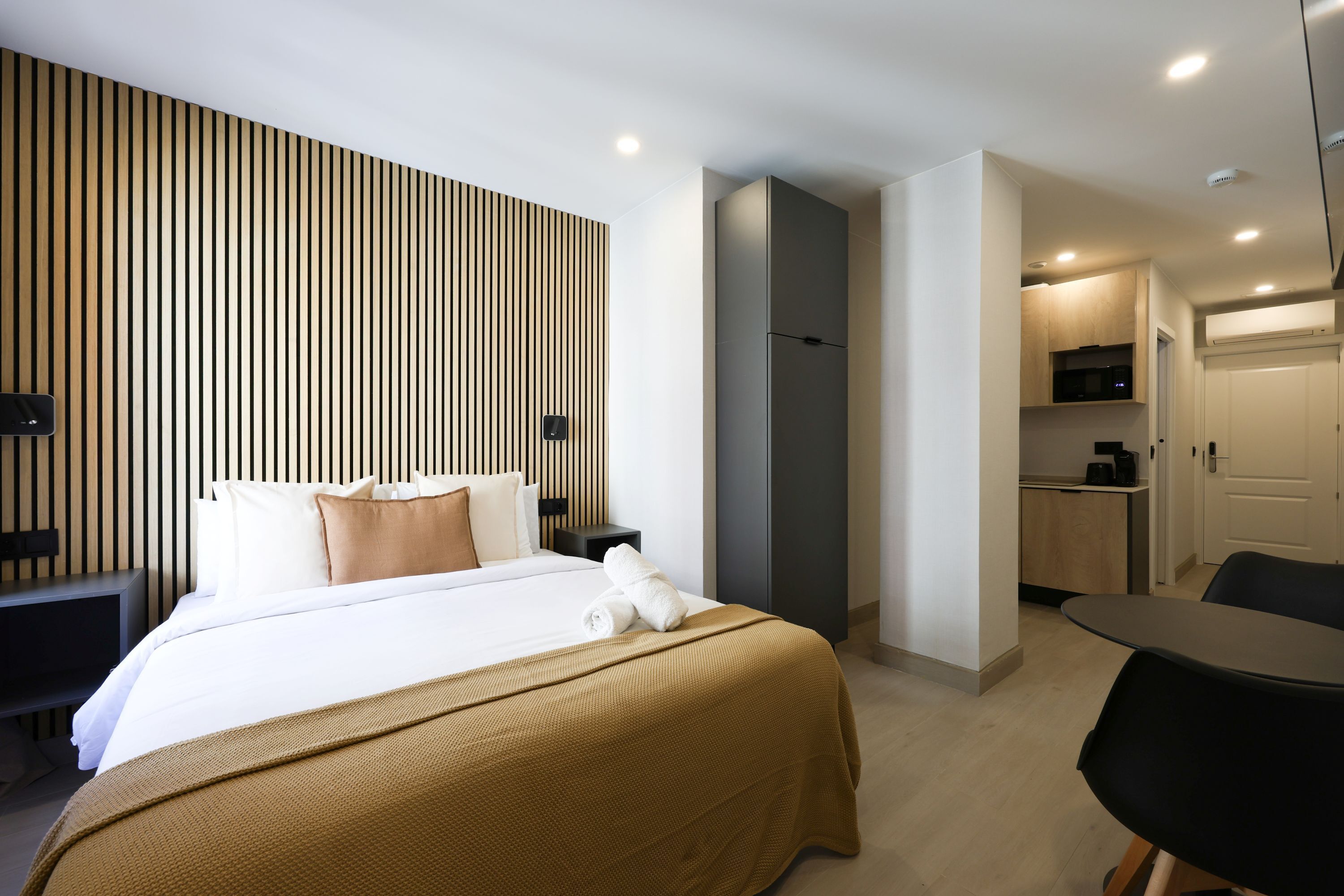 Une chambre d’hôtel avec un lit, une table de chevet et un petit coin cuisine.