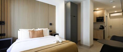 Une chambre d’hôtel avec un lit, une table de chevet et un petit coin cuisine.