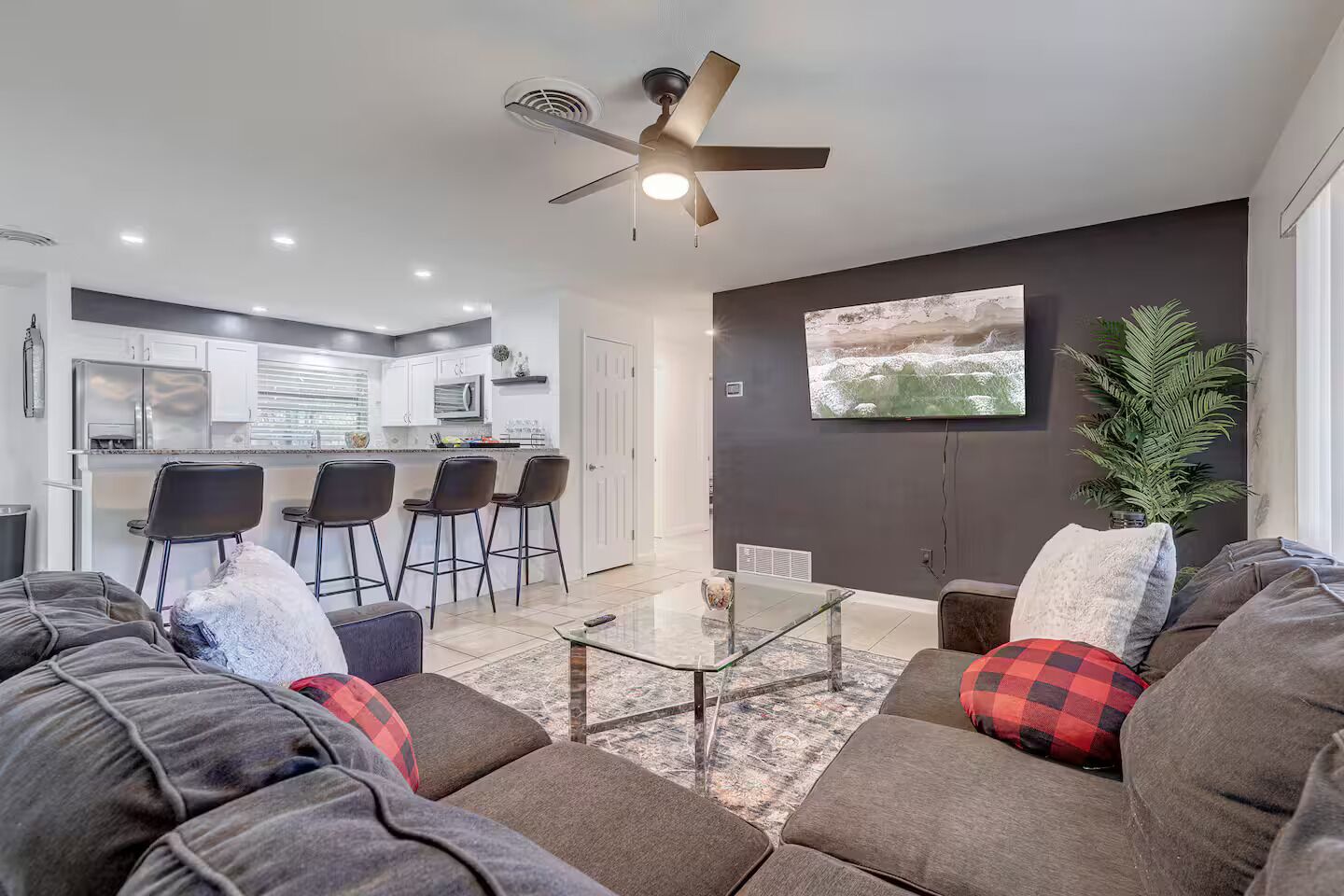 Uma sala de estar moderna com um sofá, uma mesa de centro e uma TV fixada na parede.