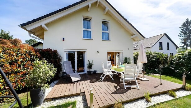 Een huis met twee verdiepingen, een terras, zitplaatsen buiten en een tuin.