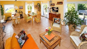 Een lichte woonkamer met een bank, een salontafel en een eethoek met stoelen en een tafel.
