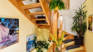 Een houten trap met een zwart beklede rustplaats, een potplant en een fruitschaal.