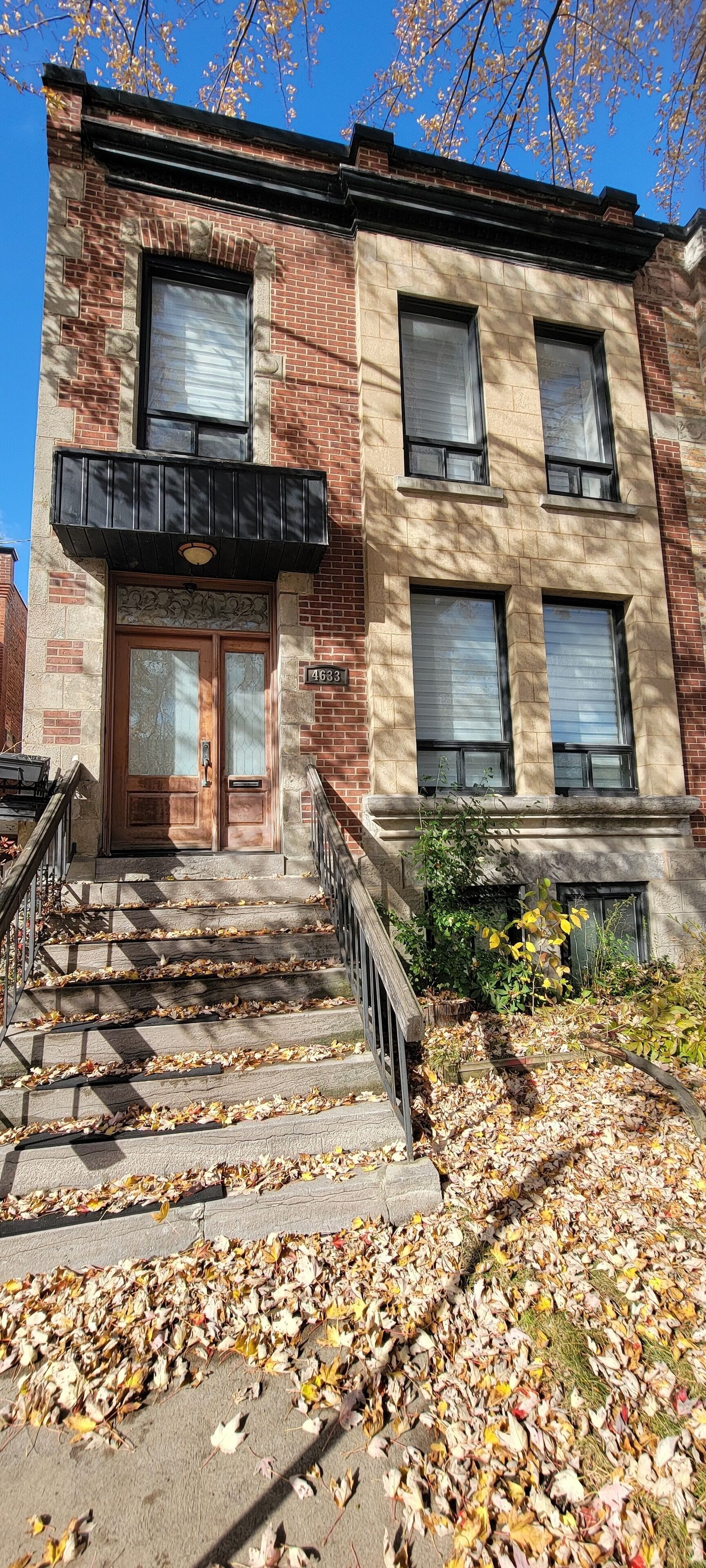 A brick building with a front entrance, a set of stairs, and a sign with the number 4633.