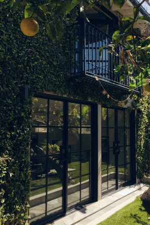 Ein Gebäude mit Glasfassade, Balkon und Garten.