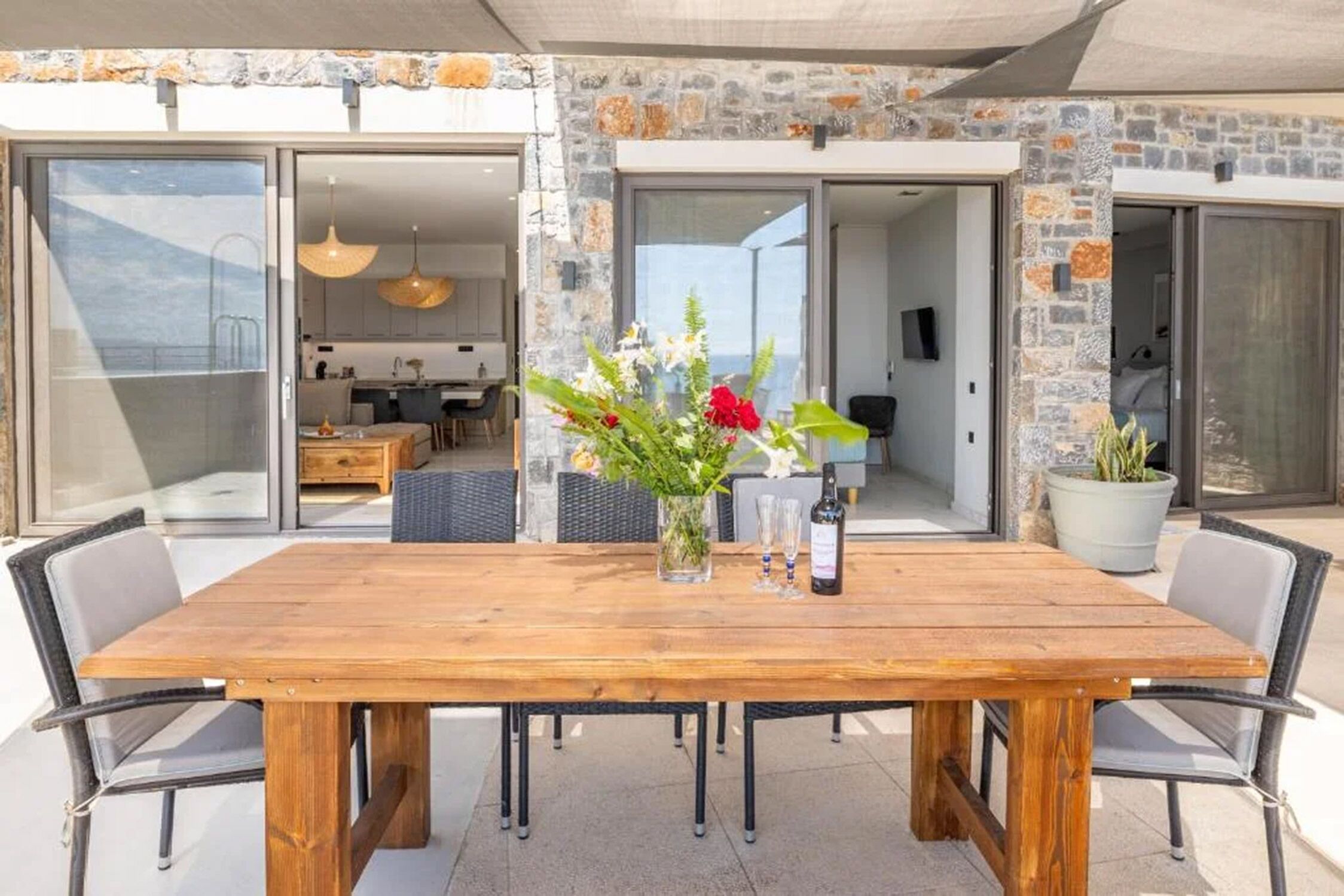 Un espace extérieur aménagé pour les repas, avec une table en bois, des chaises et un vase rempli de fleurs.