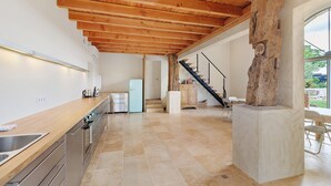 Cozinha moderna com teto de madeira, coluna de pedra e vista para a área externa.