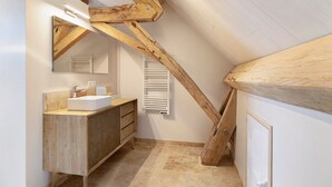 Une salle de bain avec un meuble-lavabo en bois, un grand miroir et un porte-serviettes.