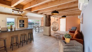 Une cuisine spacieuse avec des poutres en bois, un coin bar avec des tabourets et un espace repas avec une table et des chaises.
