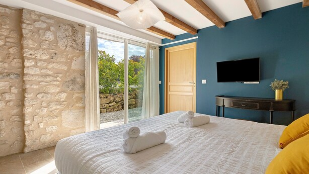 Une chambre à coucher avec un lit, une télévision, une table de chevet en bois et un mur en pierre.