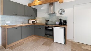 A kitchen with grey cabinets, a microwave, a coffee maker, and a dishwasher. - Gîte L'albizia - Les Carassonnes with Shared Pool, Wi-Fi and Air Conditioning (Saint-Nexans)