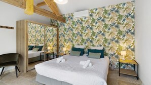 A bedroom with a bed, a mirror, a chair, and a nightstand with a lamp. - Gîte L'albizia - Les Carassonnes with Shared Pool, Wi-Fi and Air Conditioning (Saint-Nexans)