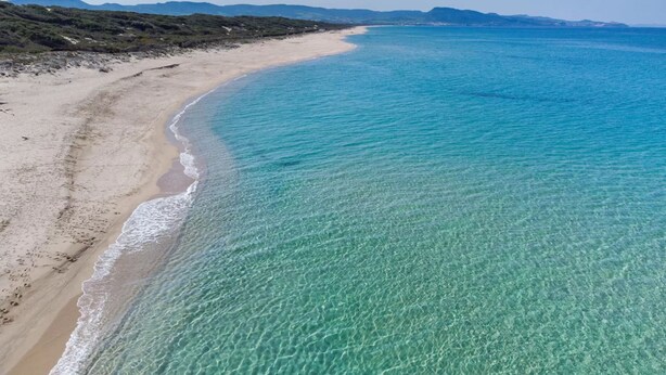 Uma praia com águas turquesa cristalinas e uma orla arenosa.