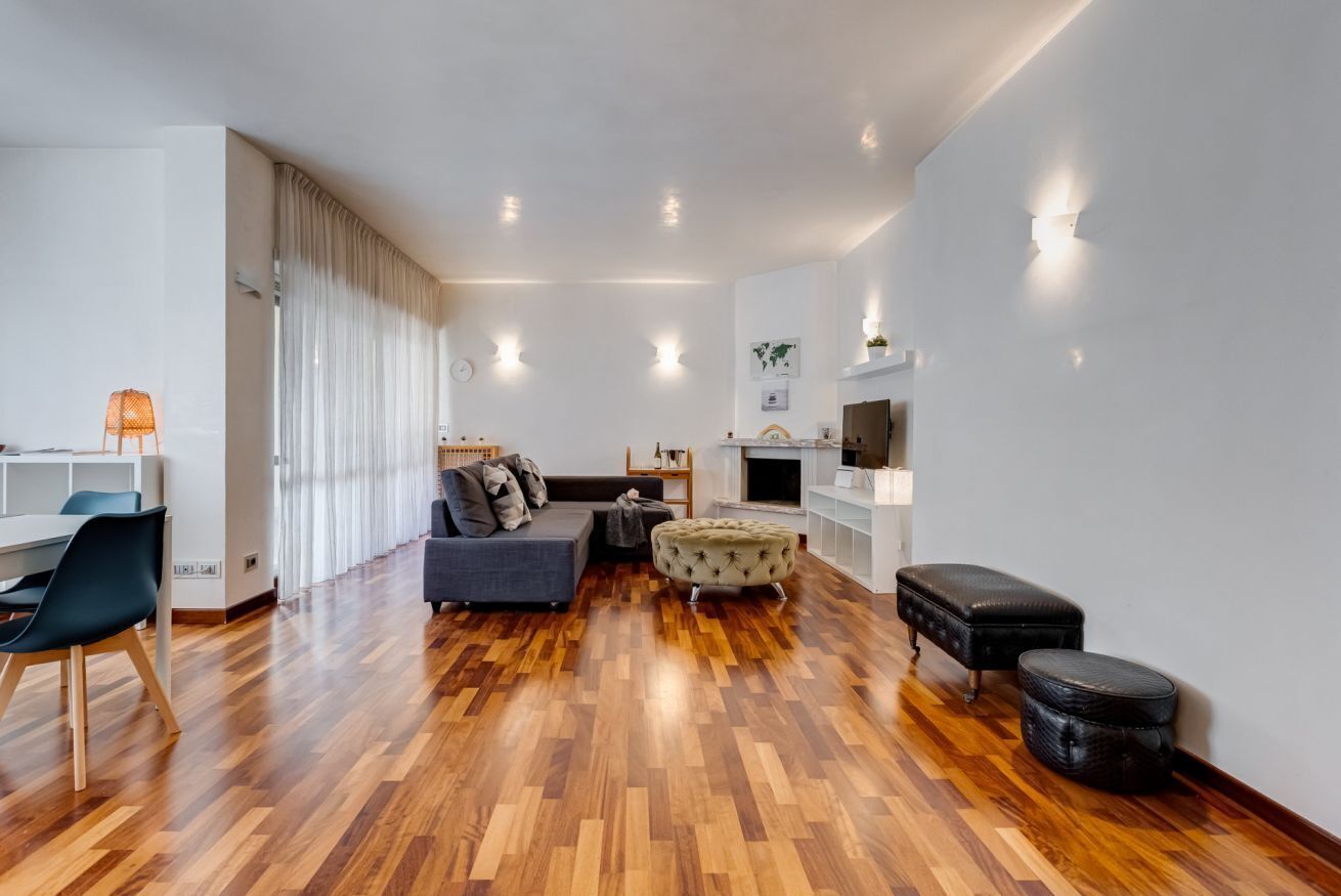Una sala de estar moderna con sofá, reposapiés y un comedor con sillas y una mesa.