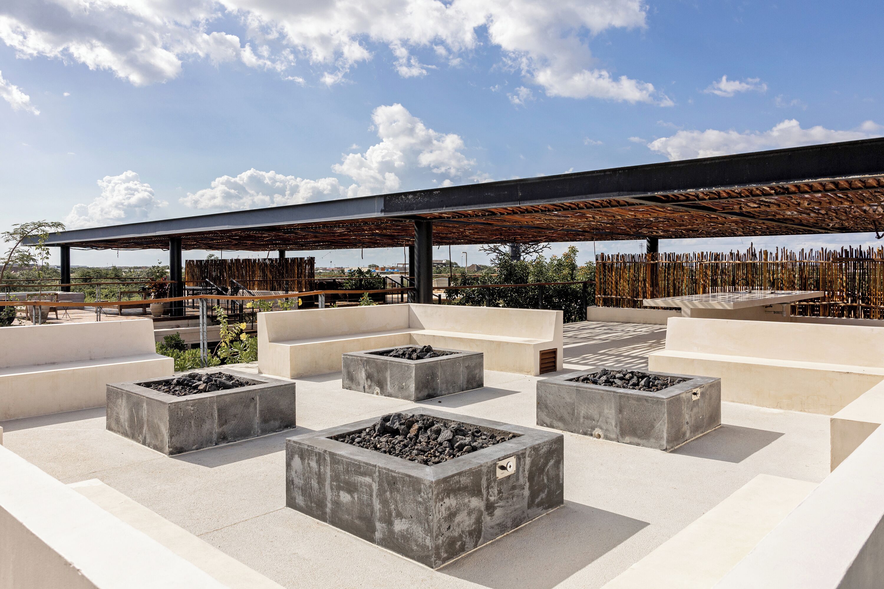 An outdoor seating area with concrete planters and a covered section.