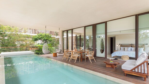 Ein moderner Poolbereich im Freien mit Holzterrasse, Essplatz und Liegestuhl.