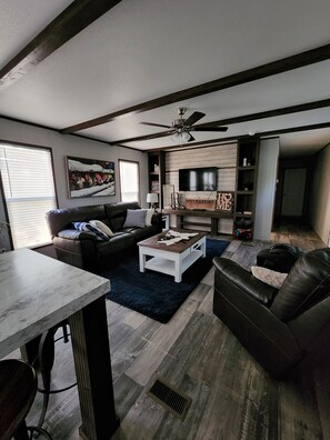 Ein modernes Wohnzimmer mit einem dunkelbraunen Ledersofa, einem weißen Couchtisch und einem an der Wand befestigten Fernseher.