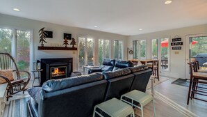 Ein geräumiges Wohnzimmer mit Kamin, Ledersofa und großen Fenstern.