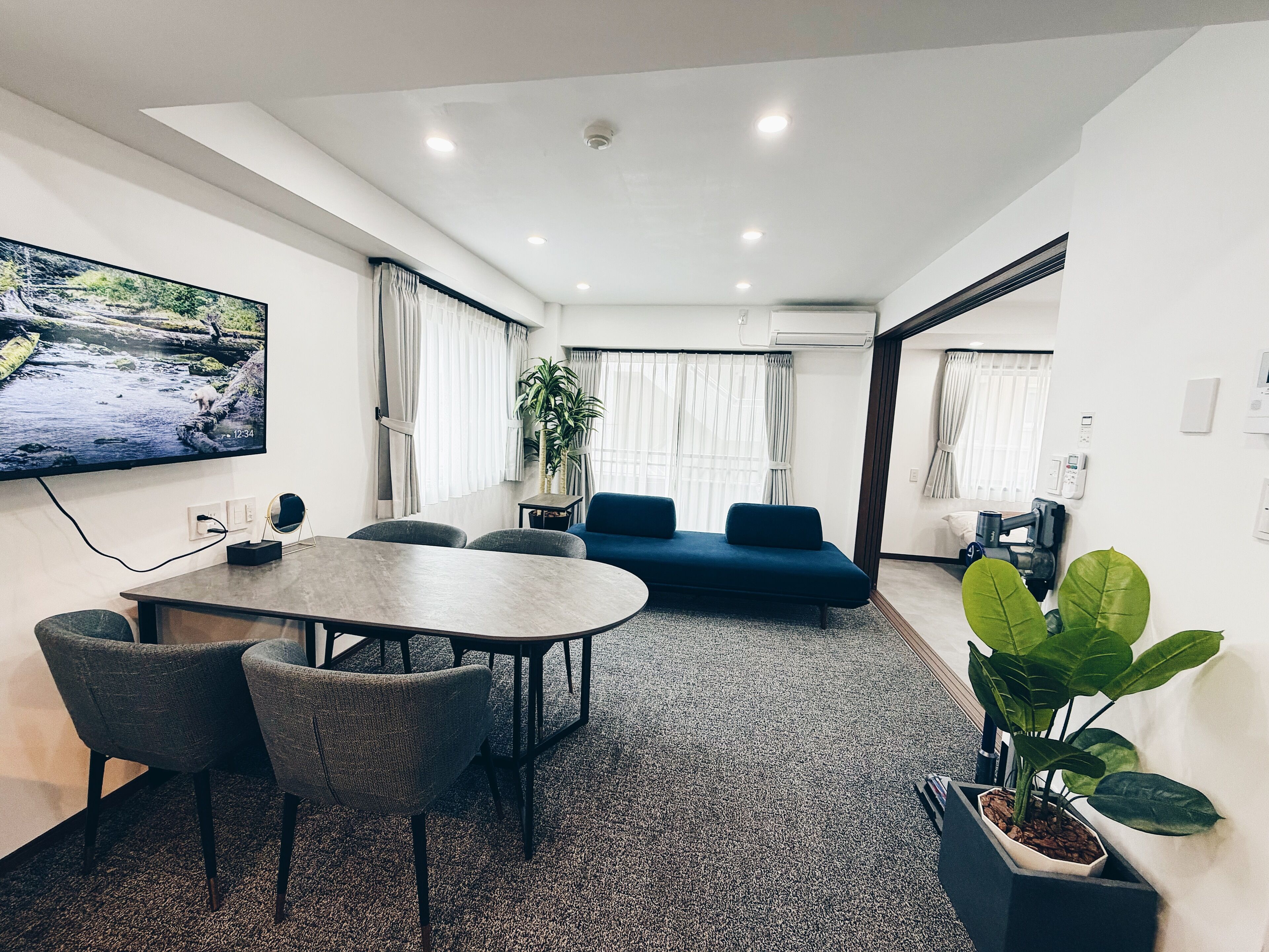 A modern living room with a TV, seating, and a large window.