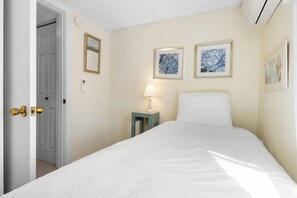 A hotel room with a bed, a nightstand with a lamp, and two framed artworks on the wall.