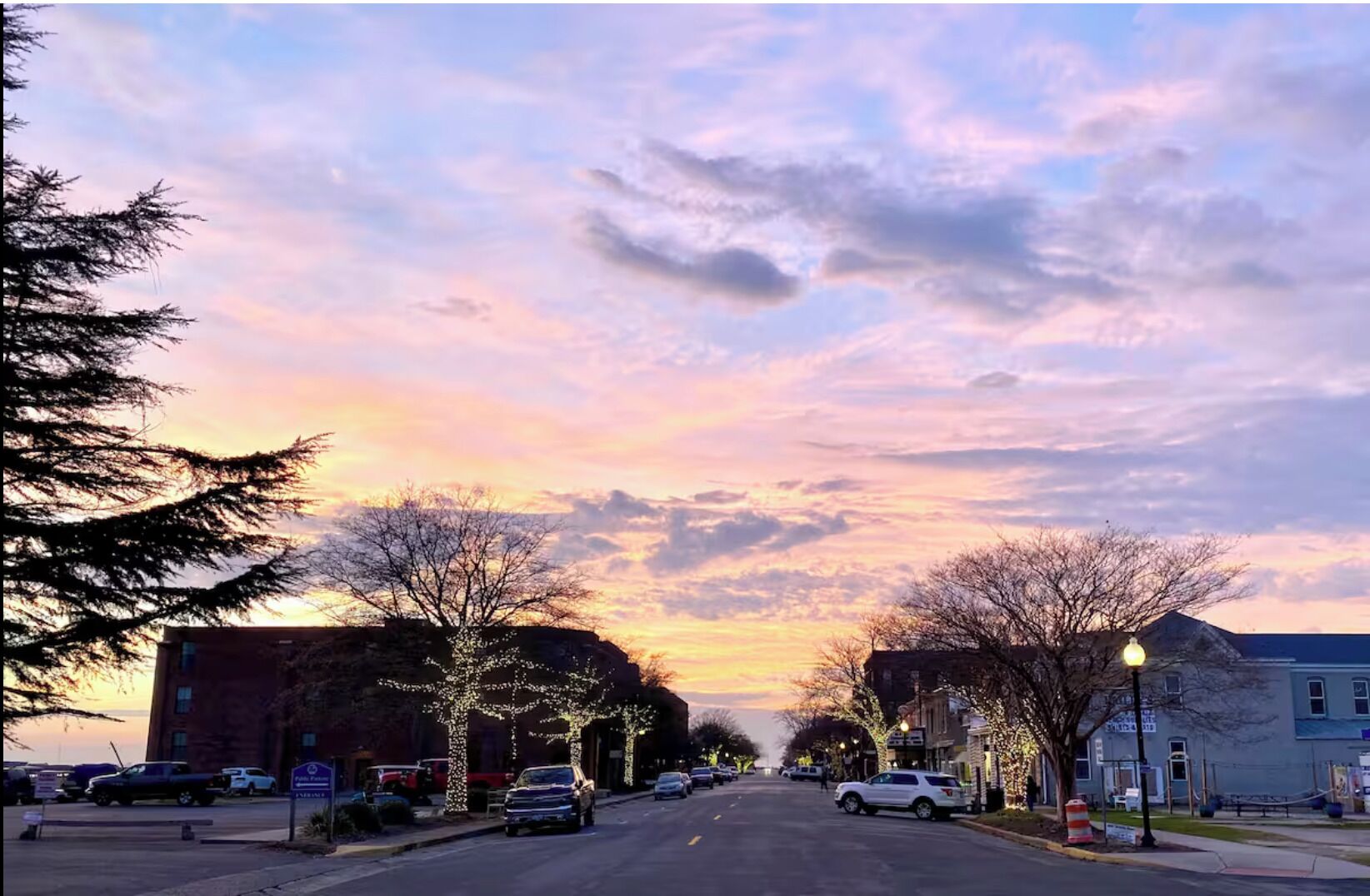 Straßenansicht im Abenddämmerung mit Gebäuden an beiden Seiten, einem klaren Himmel und Straßenlaternen.