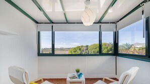 Een kamer met twee stoelen, een tafeltje en uitzicht door grote ramen.