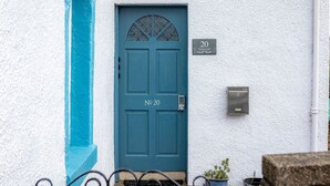 Una puerta azul con un número, un buzón y una planta en maceta.