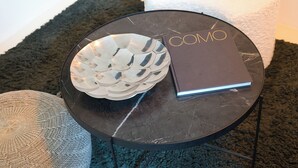 Ein runder, schwarzer Tisch mit einer verzierten Schale und einem Buch mit dem Titel "COMO".