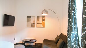 Ein modernes Wohnzimmer mit einer Couch, einem runden Couchtisch, einer Stehlampe und zwei abstrakten Wandbildern.