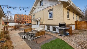 A backyard with a barbecue grill, a wooden fence, and a patio area with a bench and table. - Mathews House 4 King Beds Near CSU & Old Town (Fort Collins)