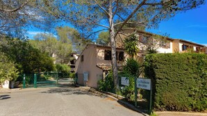 A two-story building with a tiled roof, a gated entrance, and a sign indicating 'Le Hameau des pins'. - Very nice app 150m from the beach 50m from the pool (Saint-Raphaël)