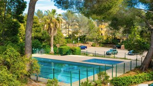 A swimming pool surrounded by greenery, with a road and parked cars in the background. - Very nice app 150m from the beach 50m from the pool (Saint-Raphaël)